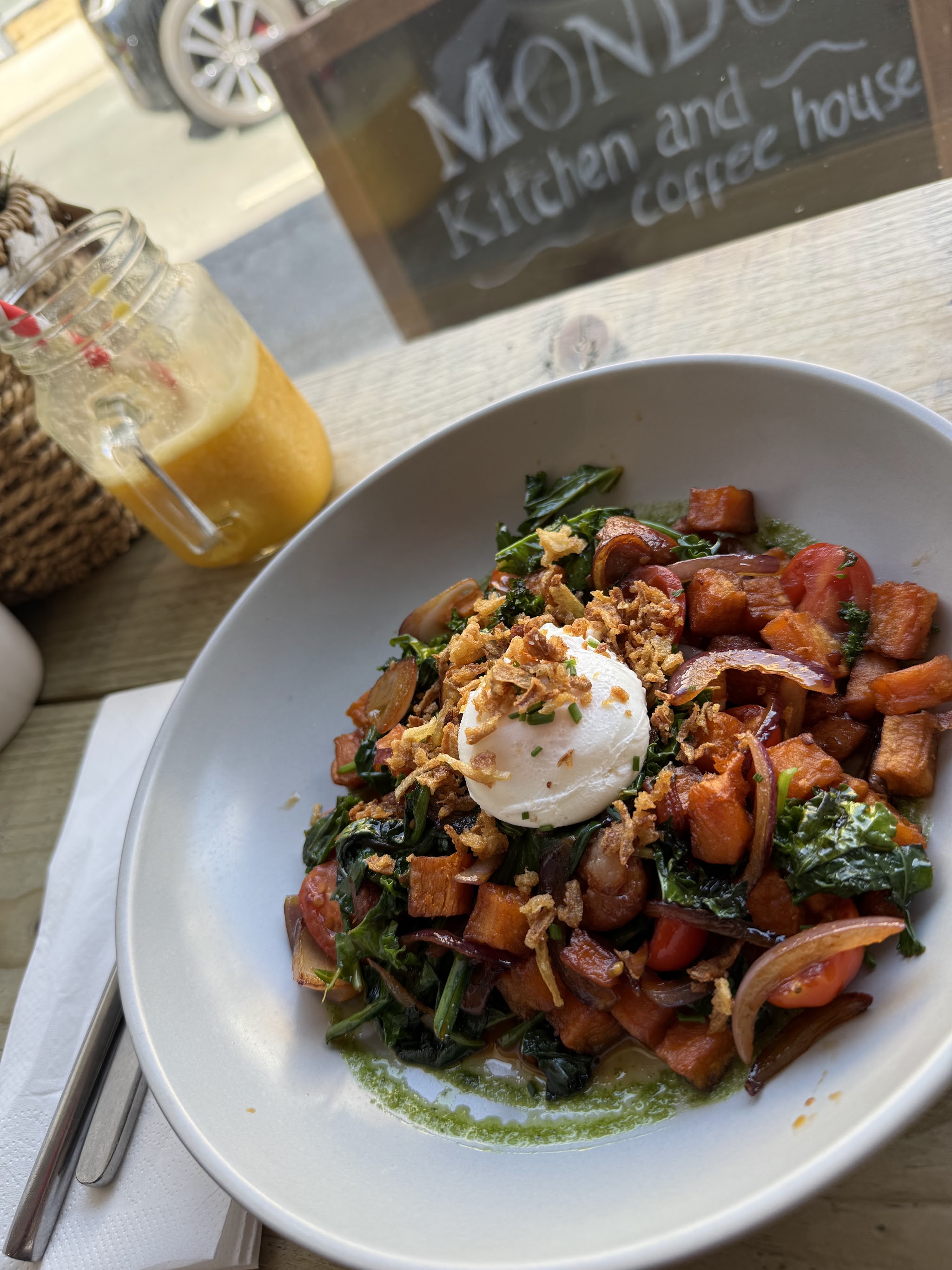 A colourful plate of food beside a fresh juice at Mondo