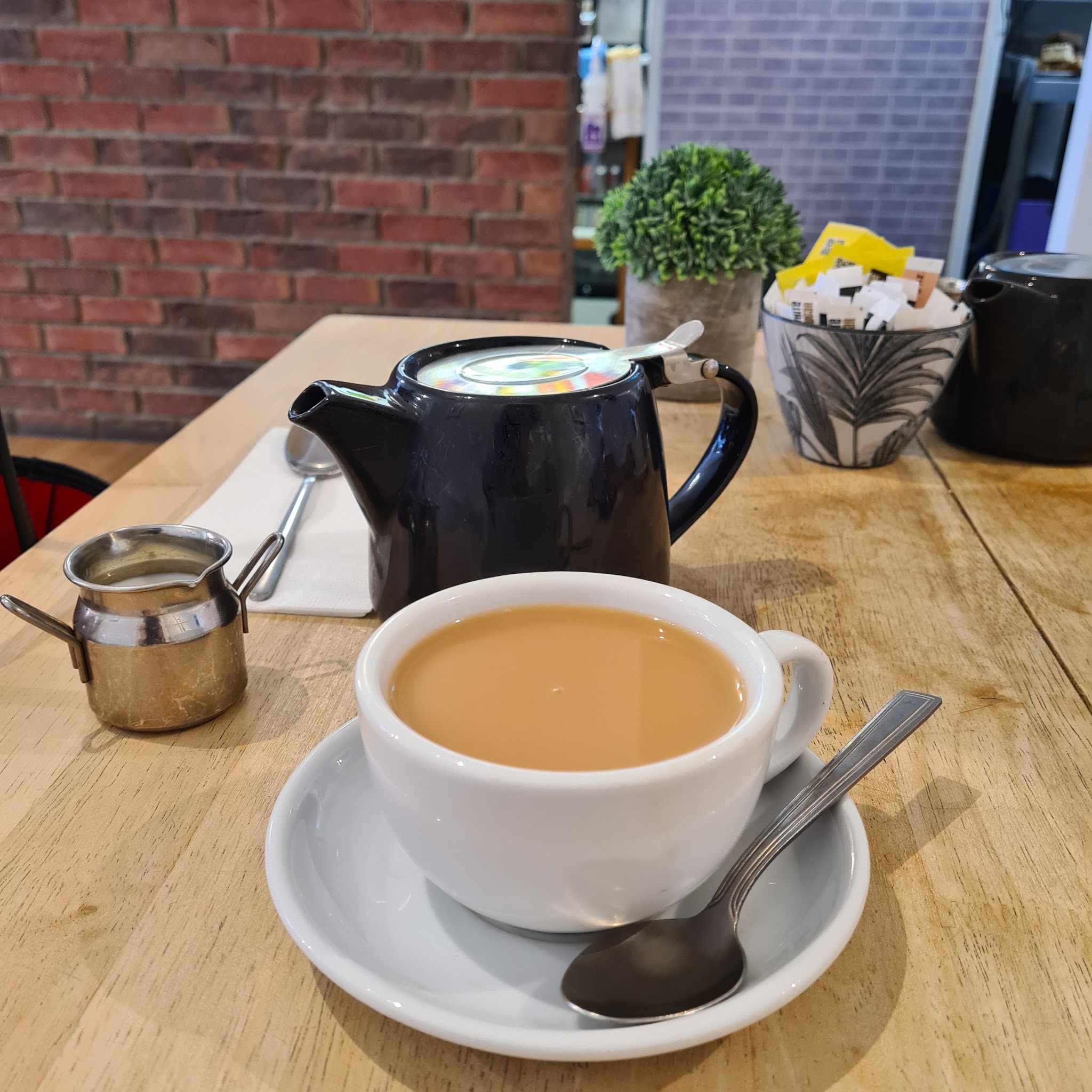 A pot of tea and a cup on a wooden table at Mondo